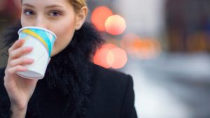 Woman drinking coffee on city sidewalk