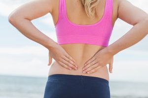 Mid section of toned woman from back pain on beach